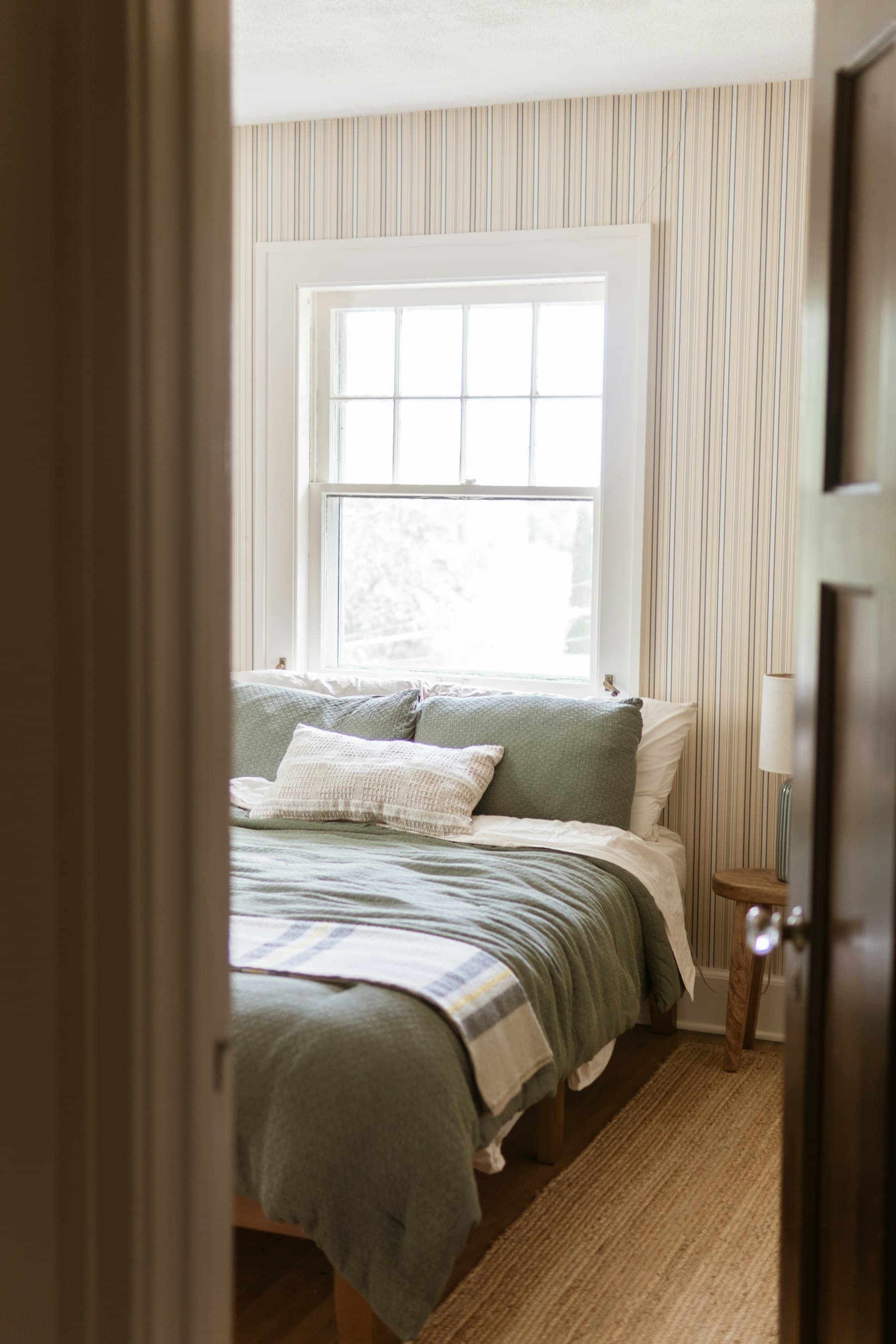 Dormitorio visto desde la puerta, con ventana de guillotina y ropa de cama en verde salvia