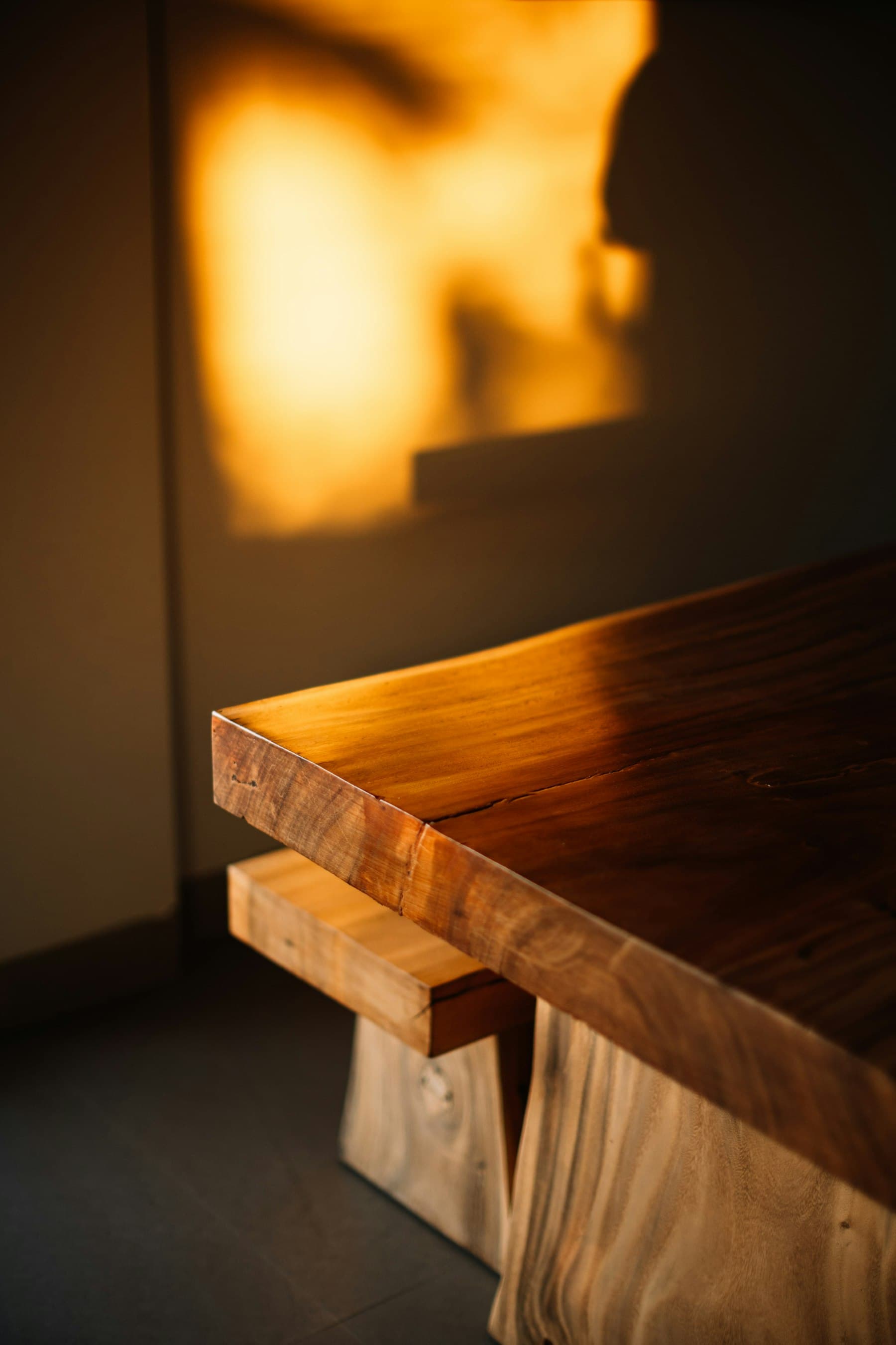 Canto de una mesa de madera maciza iluminado por la última luz del día